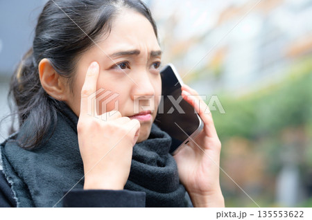 マフラーをしてスマホを使用する女性 マフラーをしてスマホを使用する女性 135553622
