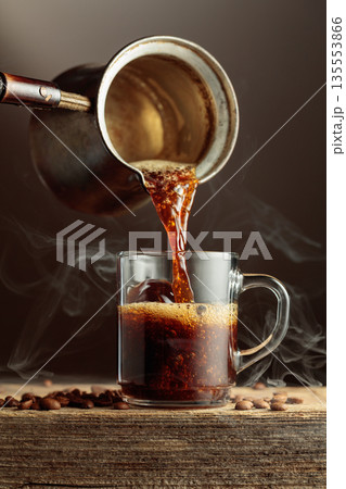 Black coffee is poured in a clear glass mug. Black coffee is poured in a clear glass mug. 135553866