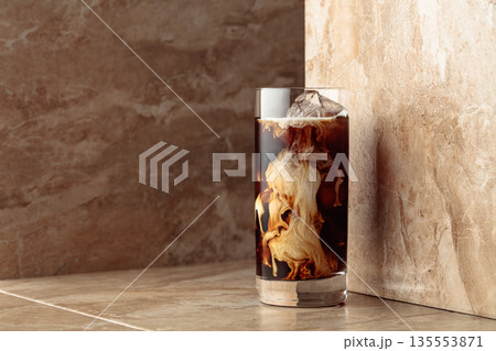 Iced coffee with cream on a beige ceramic table. Iced coffee with cream on a beige ceramic table. 135553871