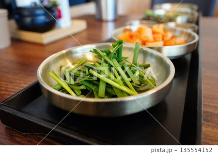 Fresh Korean garlic chives,served in a metal bowl, a popular side dish at Korean restaurants Fresh Korean garlic chives,served in a metal bowl, a popular side dish at Korean restaurants 135554152