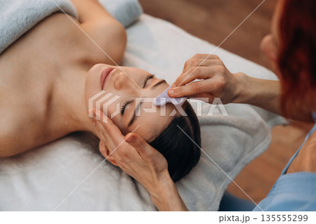In spa salon. Relaxed young woman getting massage by therapist 135555299