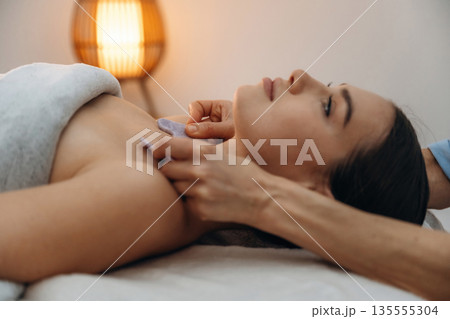 Face patches. Relaxed young woman getting massage by therapist in spa salon Face patches. Relaxed young woman getting massage by therapist in spa salon 135555304