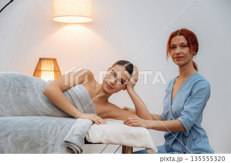 Female masseur near woman lying down in spa salon 135555320