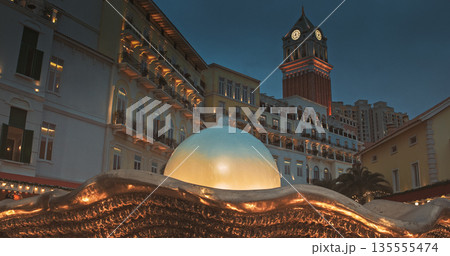 Illuminated Town Square at Night with Ornate Fountain and Luxury Residential High-Rises Illuminated Town Square at Night with Ornate Fountain and Luxury Residential High-Rises 135555474