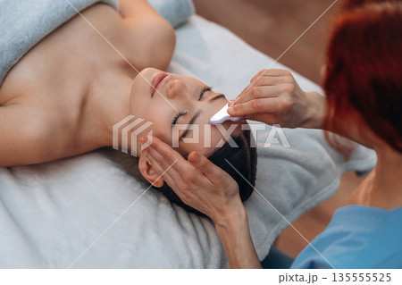 Facial massage. Relaxed young woman is with therapist in spa salon Facial massage. Relaxed young woman is with therapist in spa salon 135555525