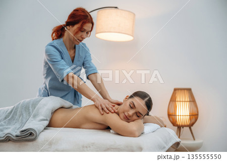 Neck massage. Relaxed young woman is with therapist in spa salon Neck massage. Relaxed young woman is with therapist in spa salon 135555550