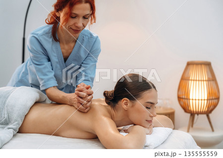 Quality service, back massage. Relaxed young woman getting massage by therapist in spa salon Quality service, back massage. Relaxed young woman getting massage by therapist in spa salon 135555559