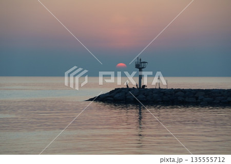golden dawn on the sea.The dawn of a red dawn on the horizon of the sky, beyond a stone pier. golden dawn on the sea.The dawn of a red dawn on the horizon of the sky, beyond a stone pier. 135555712