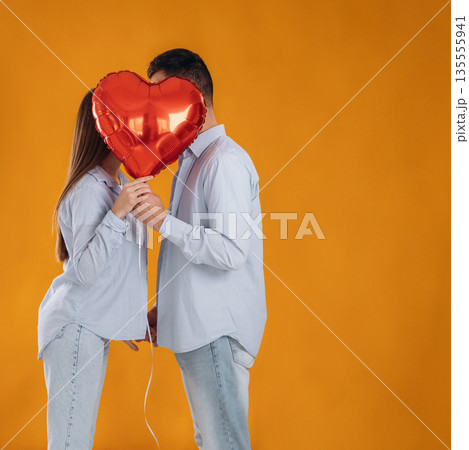 Kissing, heart shaped balloon. Lovely couple are together in the studio Kissing, heart shaped balloon. Lovely couple are together in the studio 135555941