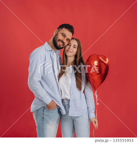 Posing, holding balloon. Lovely couple are together in the studio Posing, holding balloon. Lovely couple are together in the studio 135555953