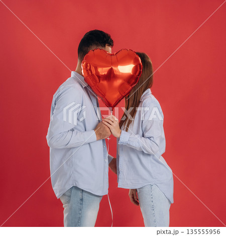 Kissing, heart shaped balloon. Lovely couple are together in the studio Kissing, heart shaped balloon. Lovely couple are together in the studio 135555956