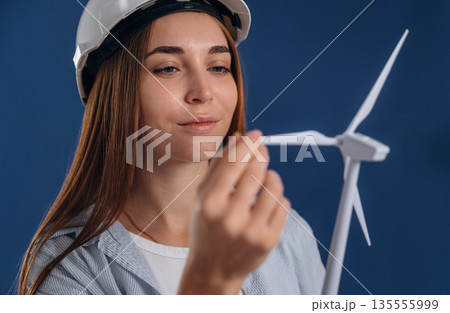 Touching the wind. Woman engineer electrician is holding toy wind generator 135555999