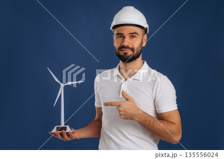 Against blue background. Electrician is holding wind generator toy, conception of eco energy 135556024