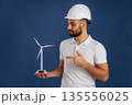 Against blue background. Electrician is holding wind generator toy, conception of eco energy 135556025