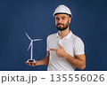 Against blue background. Electrician is holding wind generator toy, conception of eco energy 135556026