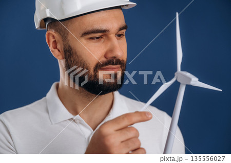 Against blue background. Electrician is holding wind generator toy, conception of eco energy 135556027