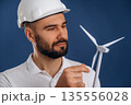 Against blue background. Electrician is holding wind generator toy, conception of eco energy 135556028