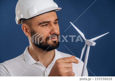 Against blue background. Electrician is holding wind generator toy, conception of eco energy 135556028