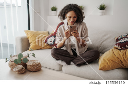 African American Woman Enjoying Morning, Woman Sitting Comfortably On Sofa With Coffee And Plants African American Woman Enjoying Morning, Woman Sitting Comfortably On Sofa With Coffee And Plants 135556130