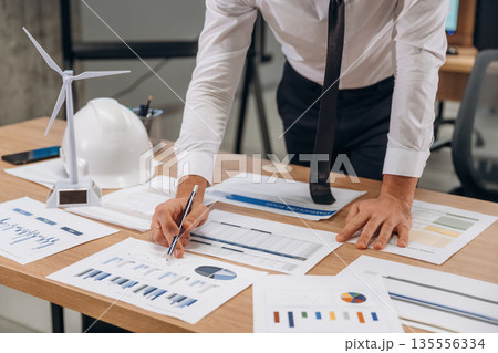 Paperwork, writing on graphs. Man is working in the wind turbine company Paperwork, writing on graphs. Man is working in the wind turbine company 135556334