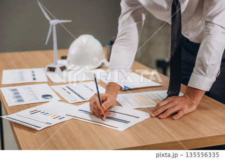 By the table with documents. Man is working in the wind turbine company By the table with documents. Man is working in the wind turbine company 135556335