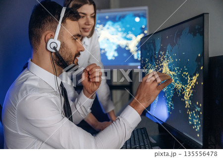 Looking at map together. People are working by computers in airline company 135556478