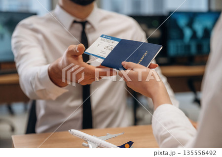 Travel and vacation time. Woman is giving boarding pass, tickets to airline company worker Travel and vacation time. Woman is giving boarding pass, tickets to airline company worker 135556492