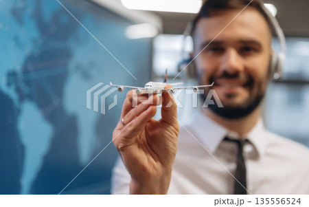 Cheerful facial expression. Man is holding toy plane, in airline company Cheerful facial expression. Man is holding toy plane, in airline company 135556524