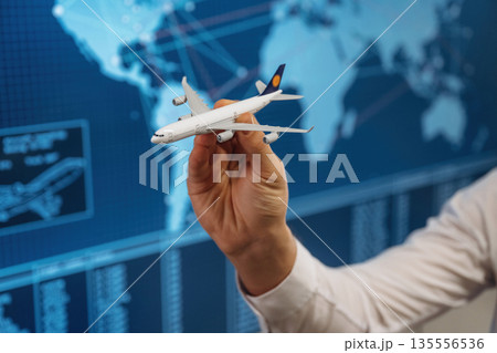 Against blue map. Close up view of hand that is holding toy plane 135556536