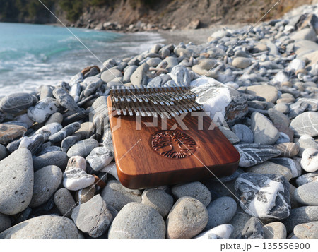 Kalimba musical instrument on stones by sea. Nature near mountains, music, and meditation. Relaxation and mental health.  135556900