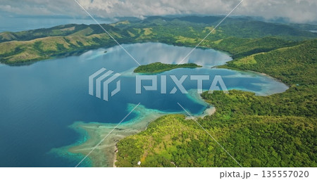 Islands covered with lush green rainforests surrounding a tranquil turquoise bay, featuring shallow coral reefs reflecting clear waters and an overcast sky Islands covered with lush green rainforests surrounding a tranquil turquoise bay, featuring shallow coral reefs reflecting clear waters and an overcast sky 135557020