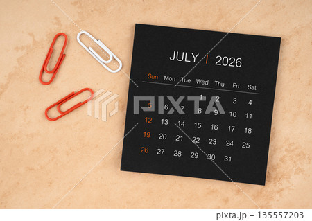 Black calendar sheet for July 2026 with paper clips on paper. 135557203