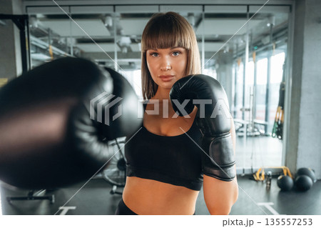 Quality boxing gloves. Young woman is in the gym Quality boxing gloves. Young woman is in the gym 135557253