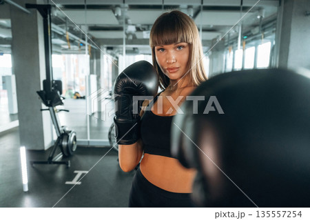 Quality boxing gloves. Young woman is in the gym Quality boxing gloves. Young woman is in the gym 135557254