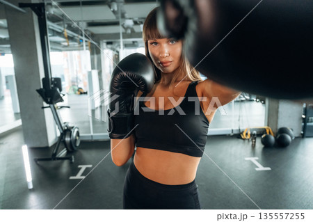 Quality boxing gloves. Young woman is in the gym Quality boxing gloves. Young woman is in the gym 135557255