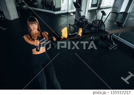 Top view, with ropes, pulls. Young woman is in the gym 135557257