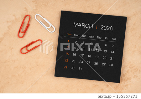 Black calendar sheet for March 2026 with paper clips on paper. 135557273