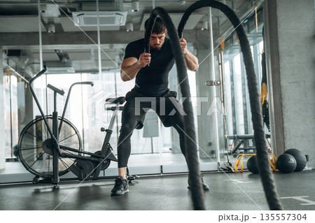 Endurance cross fit with knots. Man is in the modern gym Endurance cross fit with knots. Man is in the modern gym 135557304
