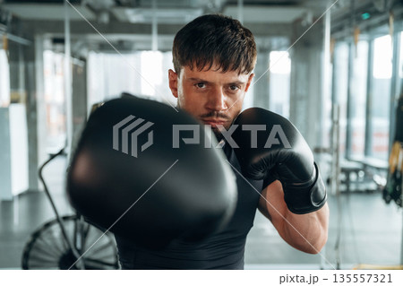 Black boxing gloves. Man is in the modern gym Black boxing gloves. Man is in the modern gym 135557321