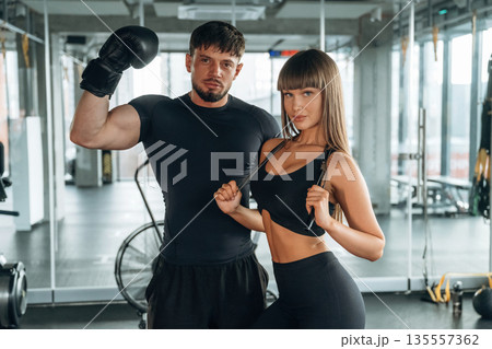 In boxing gloves. Man and woman are in the gym together In boxing gloves. Man and woman are in the gym together 135557362