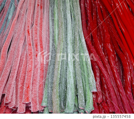 A selection of handmade gummy jelly sweets displayed in vivid colors. These treats are arranged neatly at a market stall for customers to view and enjoy. 135557458