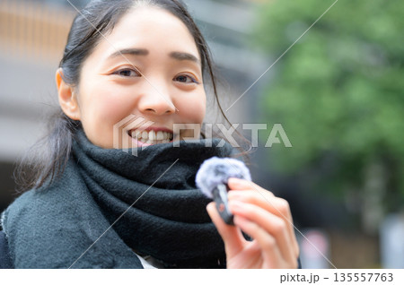 街中でピンマイクを持って話す女性 135557763