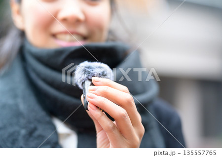 街中でピンマイクを持って話す女性 街中でピンマイクを持って話す女性 135557765