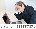 ノートPCの前で悩むスーツ姿のシニア男性 135557871