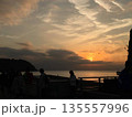 オレンジ色の夕焼けを飛ぶ一羽の鳥 135557996
