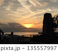 オレンジ色の夕焼けを飛ぶ一羽の鳥 135557997
