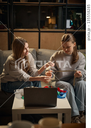 Sisters measuring decorative ribbon for handmade project at home. Sisters measuring decorative ribbon for handmade project at home. 135558285