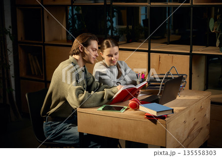 Older brother helping sister study at home desk. Older brother helping sister study at home desk. 135558303