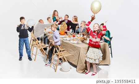 Multi generation family raising glasses during home celebration. 135558411