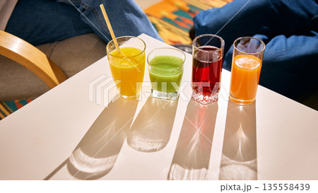 Assorted fresh juices in glasses on bright table with sunlight 135558439